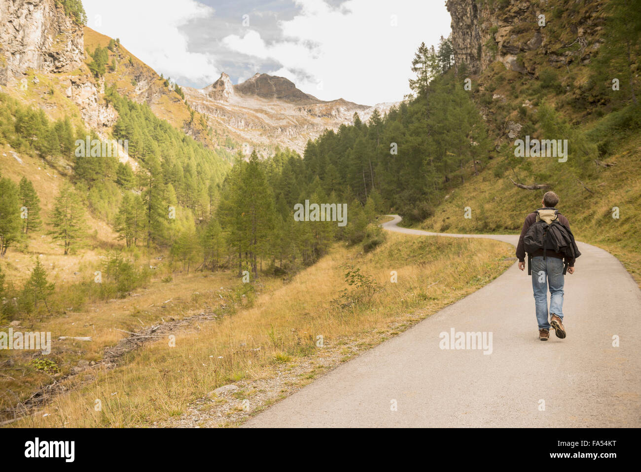 Rückansicht des Reifen Wanderer zu Fuß auf der Straße, Österreichische Alpen, Kärnten, Österreich Stockfoto