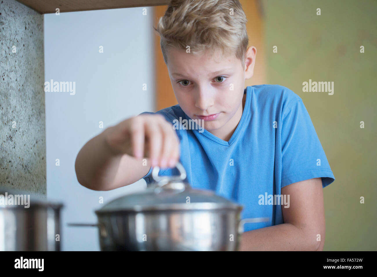 Junge Deckelöffnen der Bratpfanne sorgfältig, Freiburg Im Breisgau, Baden-Württemberg, Deutschland Stockfoto