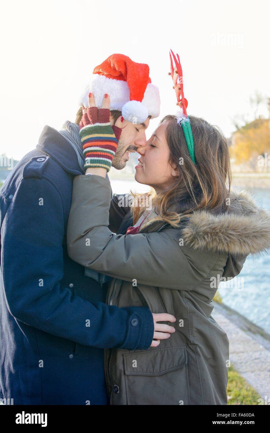 Paar in Liebe stehen im Freien mit Weihnachtsmützen Stockfoto