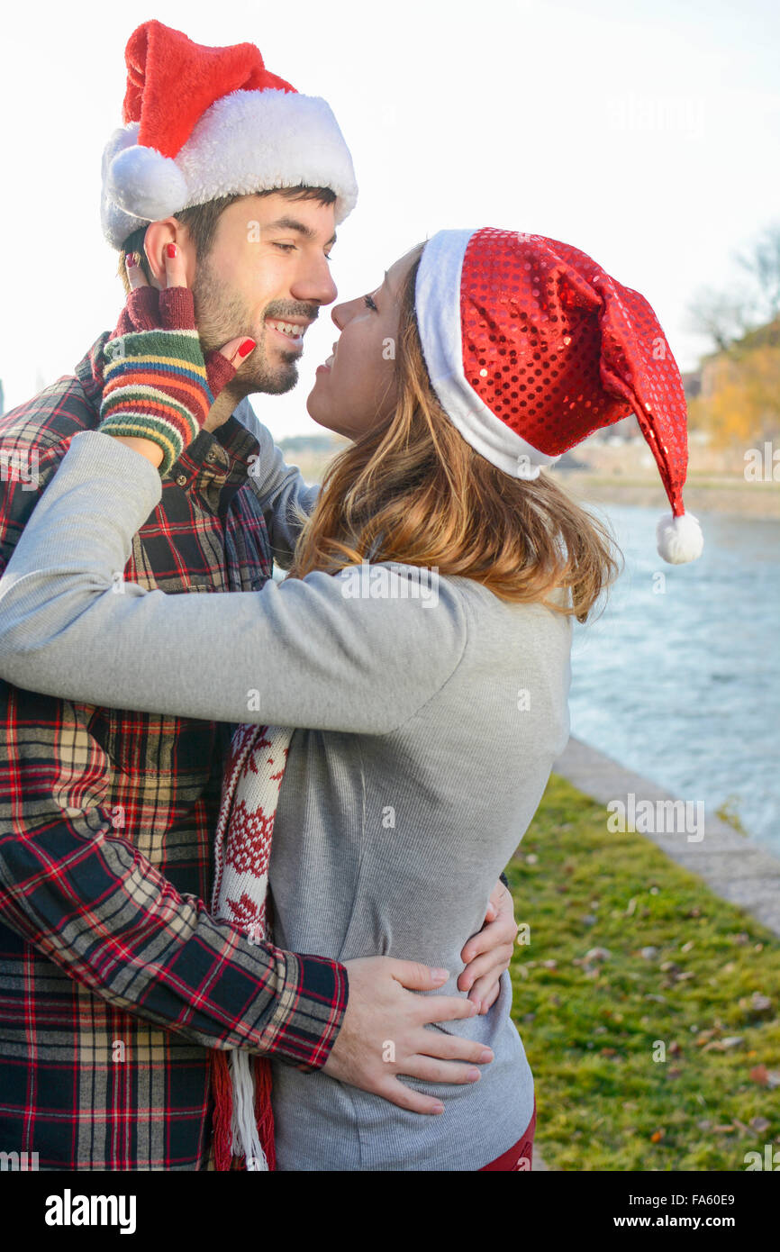 Paar in Liebe küssen im Freien mit Weihnachtsmützen Stockfoto