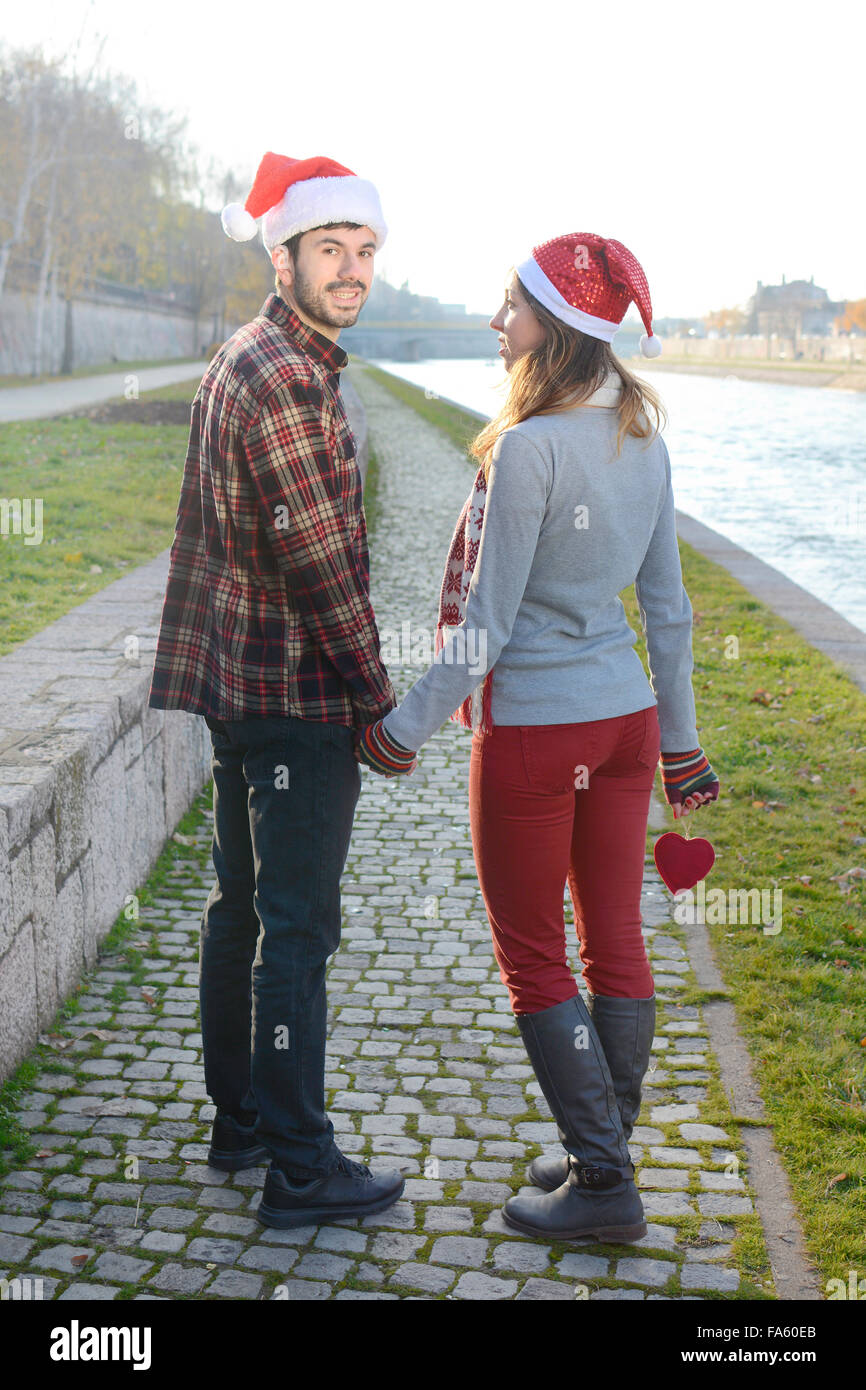 Paar in Liebe zu Fuß im freien Hand in Hand mit Weihnachtsmützen Stockfoto
