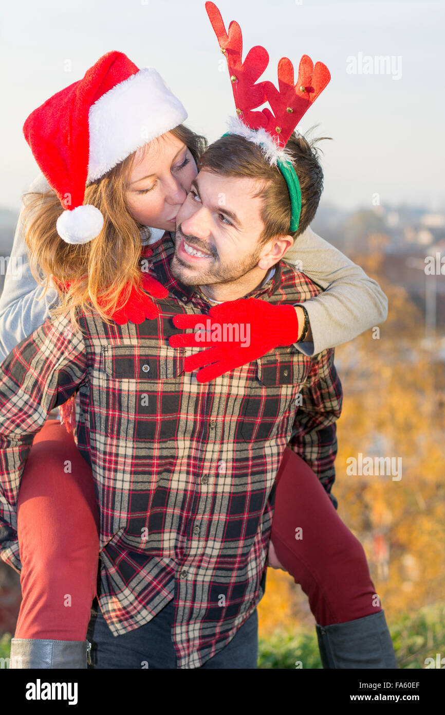 Paar in Liebe Huckepack Reiten im Freien mit Weihnachtsmützen Stockfoto