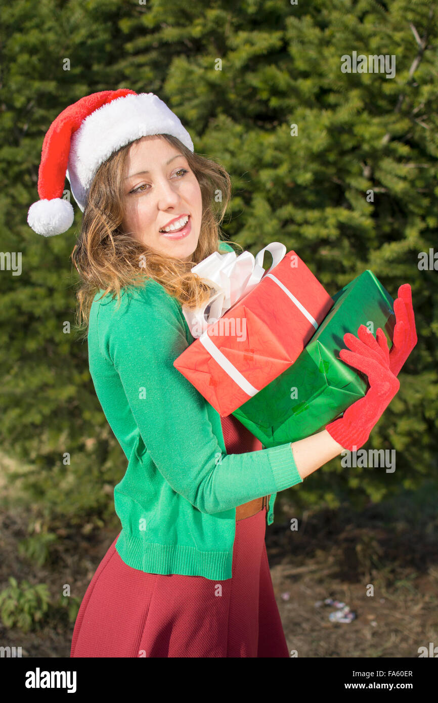 Schönes Santa Claus Mädchen mit Weihnachten präsentiert vor großen Tanne Stockfoto