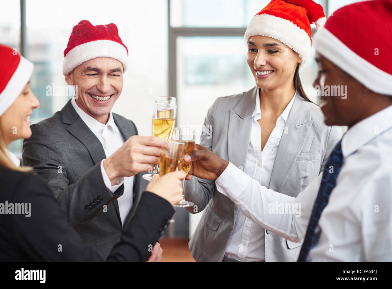 Glückliche Kollegen in Santa Kappen Toasten mit Champagner am Firmenfeier Stockfoto