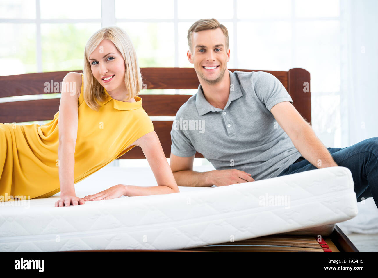 Junges Paar sitzt auf weißen Bett Stockfoto