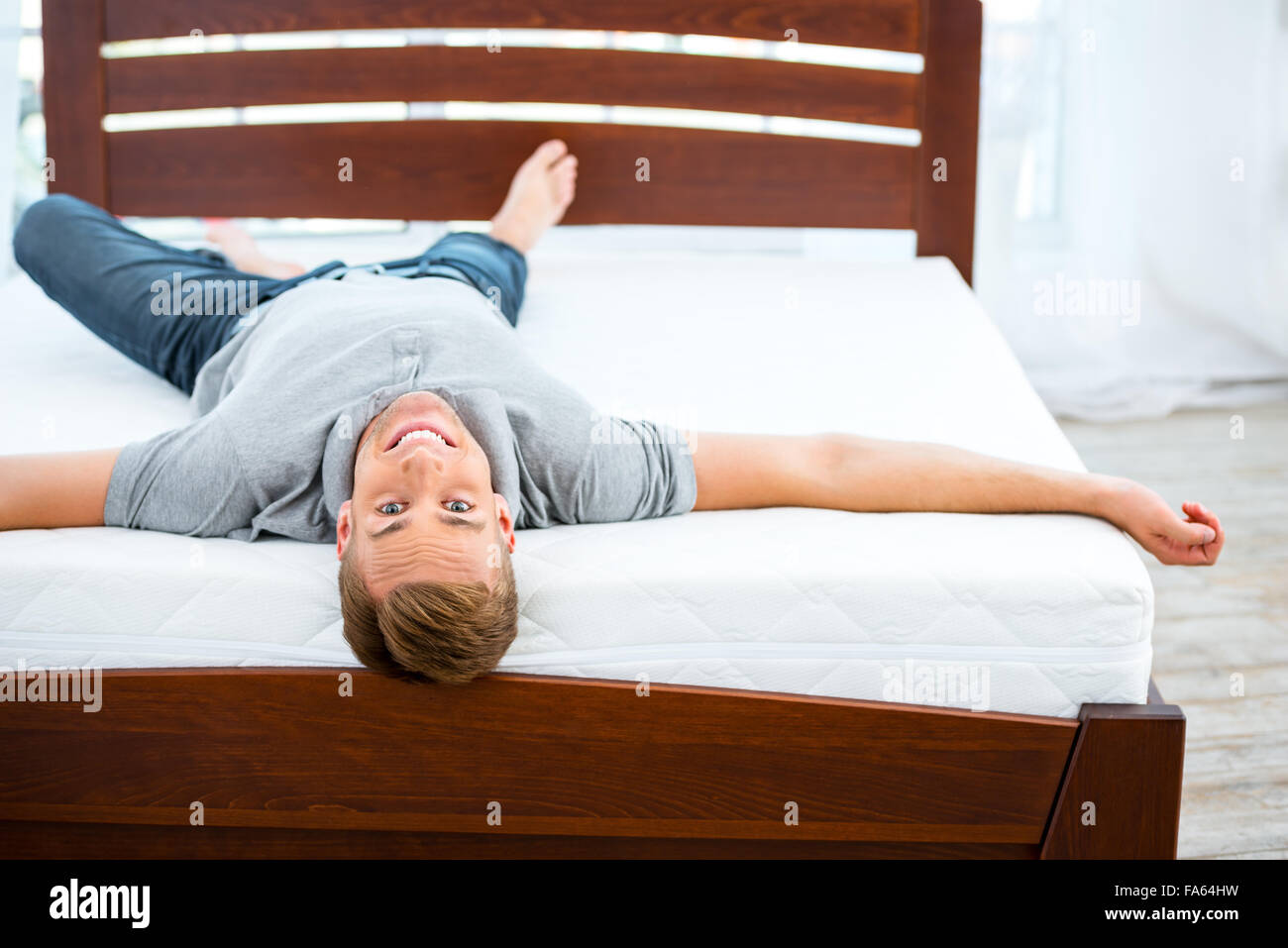 Junger Mann auf weißen Bett liegend Stockfoto