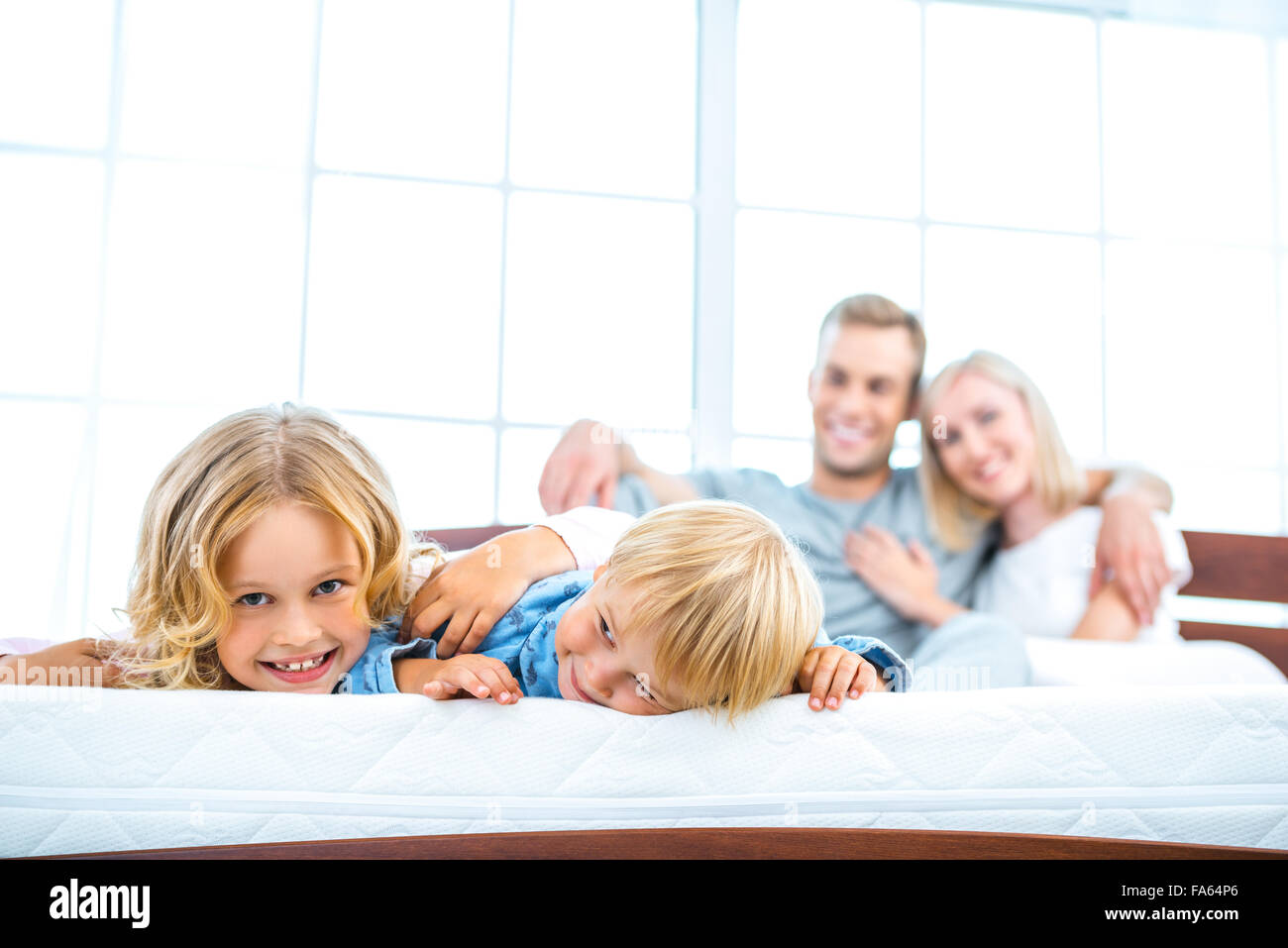 Junge Familie, die auf weißen Bett liegend Stockfoto