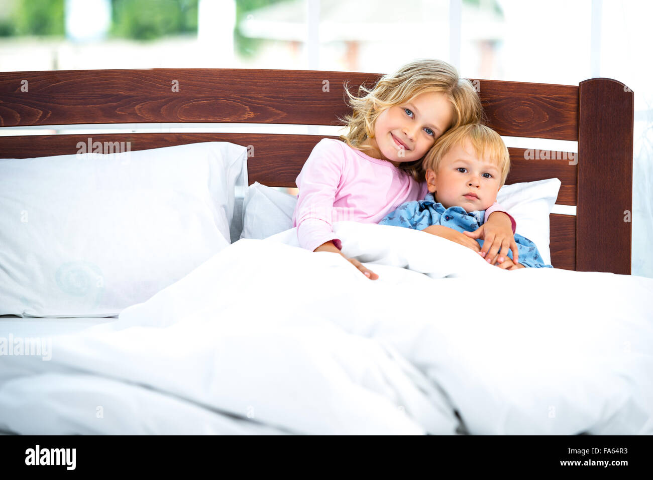 Kleine Mädchen und Jungen auf weißen Bett Stockfoto