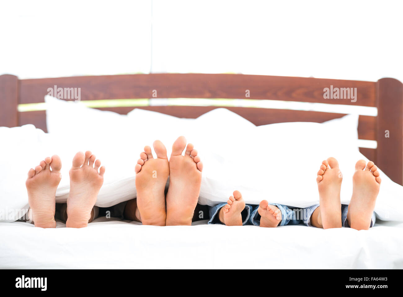 Junge Familie auf weißen Bett Stockfoto