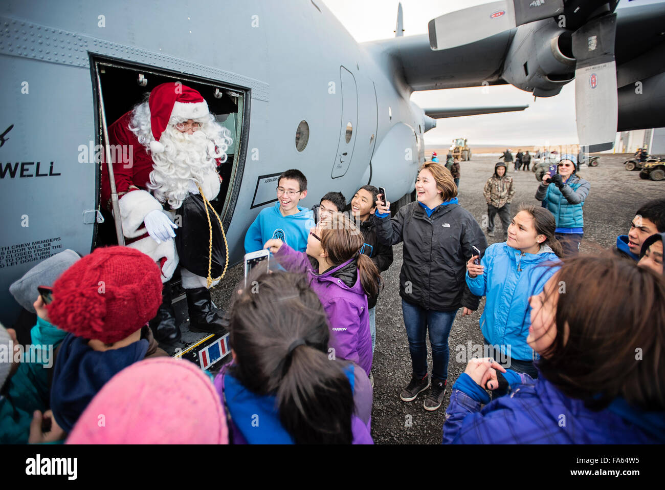 Santa Claus grüßt Native Alaskan Kinder, als er eine US Luftwaffe c-130 Hercules-Flugzeuge für einen Besuch in abgelegenen Dörfern im Rahmen der Operation Santa Claus 16. Oktober 2015 in Savoonga, Alaska die Schritte. Das Programm hat seit 59 Jahren statt und bringt Weihnachtsstimmung in unterversorgten, abgelegenen Dörfern quer durch Alaska. Stockfoto