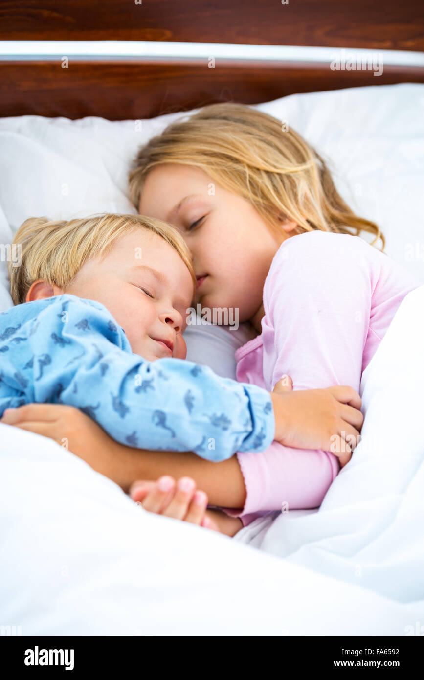 Kleine Mädchen und Jungen auf weißen Bett schlafen Stockfoto