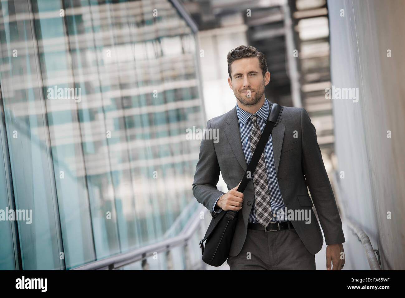 Ein Mann mit einer Computertasche mit einem Gurt auf einem Stadt-Steg. Stockfoto