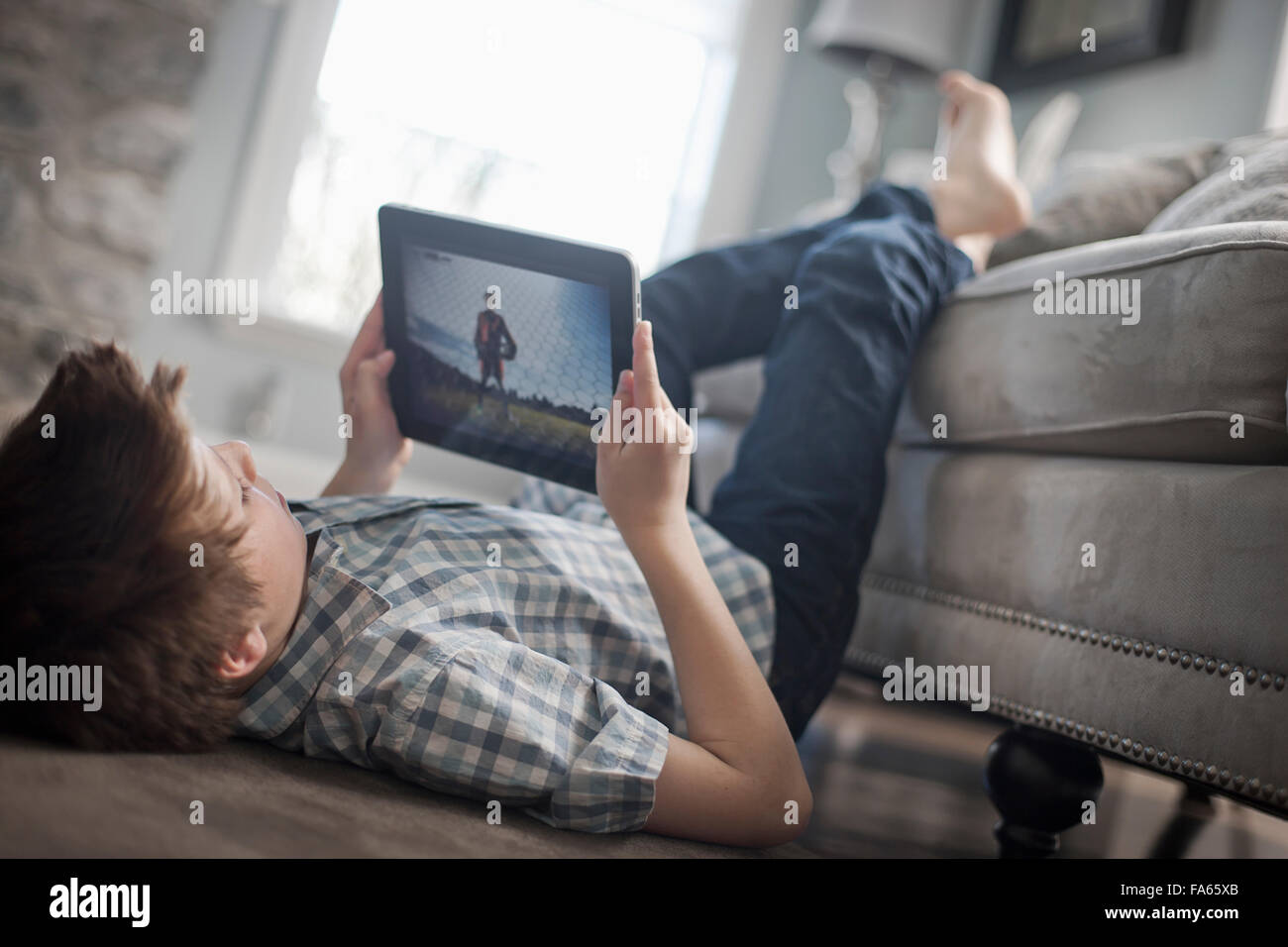 Ein Junge auf seinem vorne auf dem Boden liegend betrachtet man ein digital-Tablette. Stockfoto