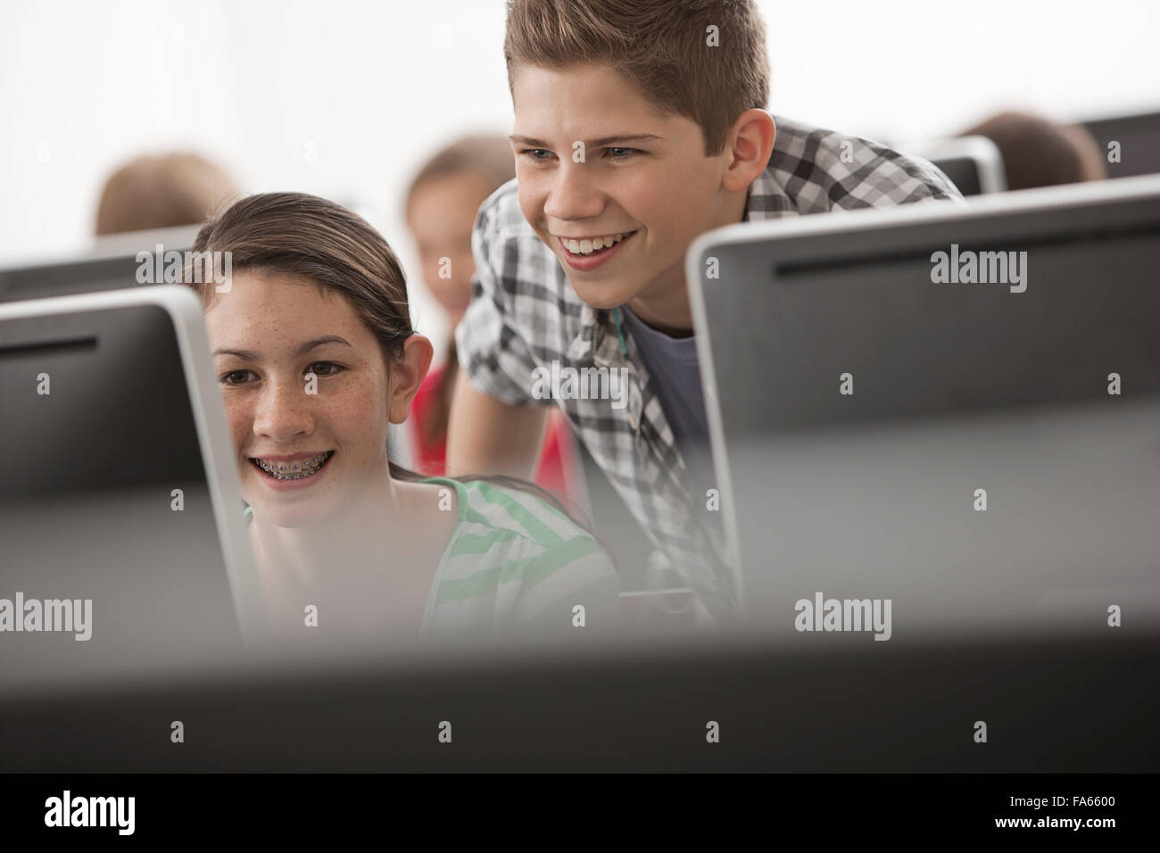 Eine Schule Computer Lab Raum, mit Reihen von Bildschirmen. Zwei Jugendliche Blick unverwandt auf dem Bildschirm. Stockfoto