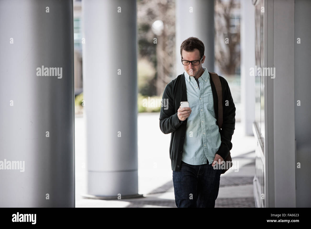 Ein Mann in Freizeitkleidung außerhalb eines Gebäudes stehen, sein Smartphone überprüfen. Stockfoto