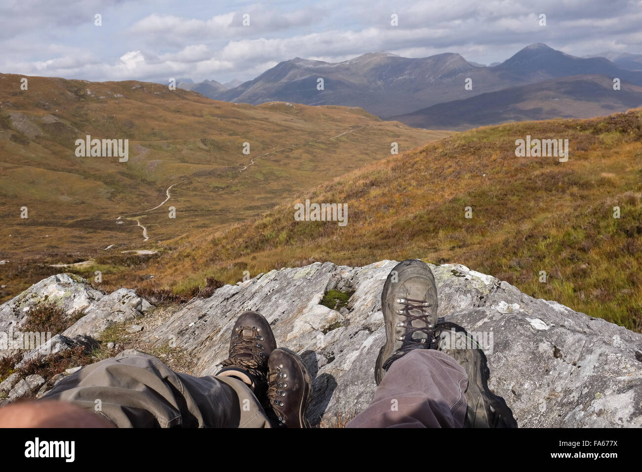 Zwei Paar Beine gestreckt auf Felsen, Highlands, Schottland, Großbritannien Stockfoto