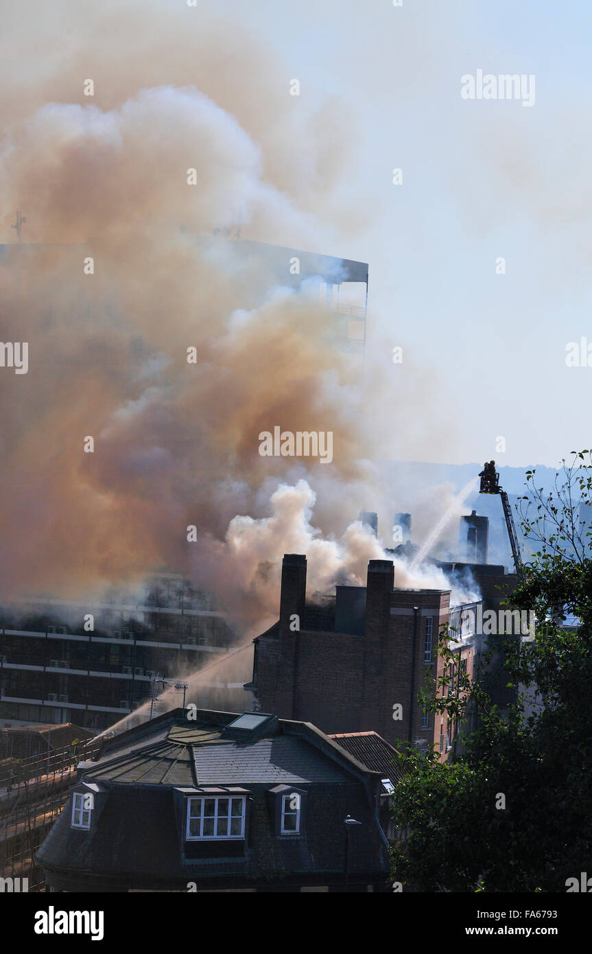 Hochhaus-Brand mit starken schwarzen Rauch und Leiter Motor Besprühen mit Wasser Stockfoto