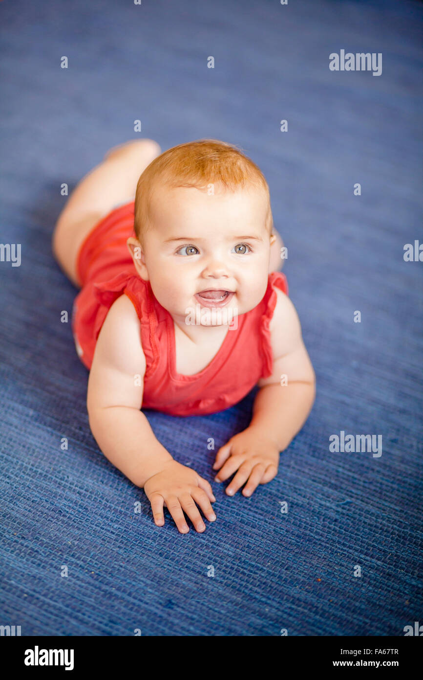 Porträt von einem lächelnden Babymädchen am Boden liegend Stockfoto