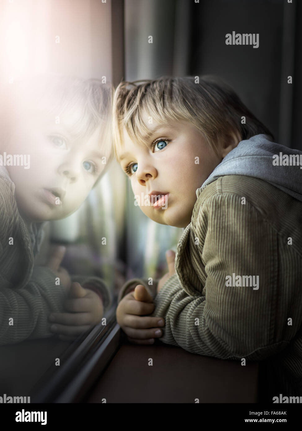 Junge Blick durch Fenster Stockfoto
