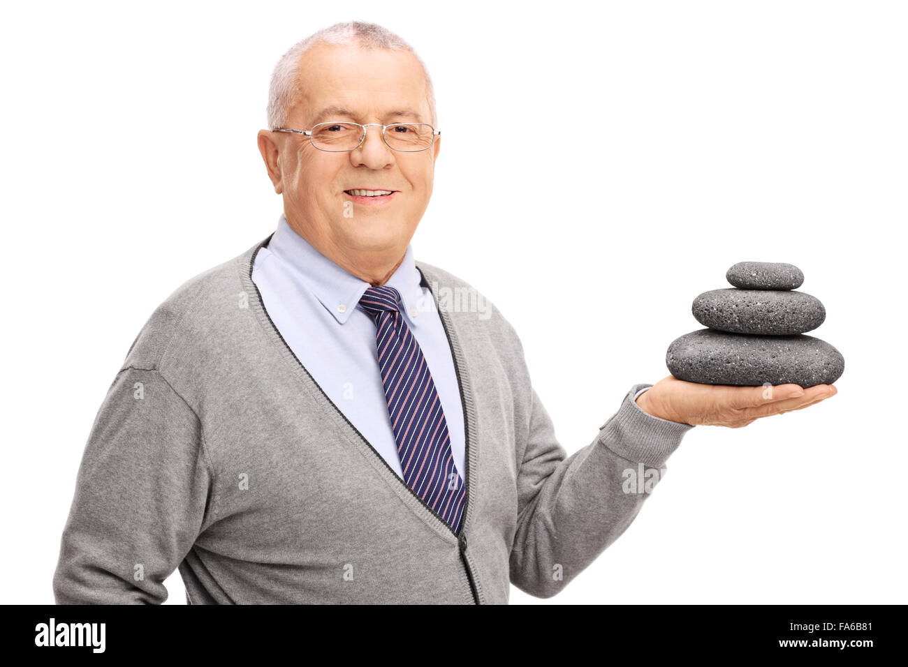 Studioaufnahme eines senior Gentleman halten eine ausgewogene Steinhaufen und in die Kamera schaut isoliert auf weißem Hintergrund Stockfoto