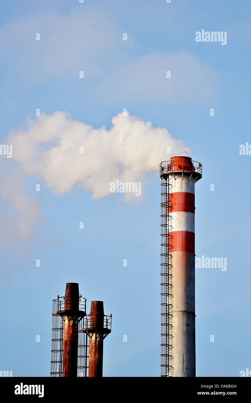 Rauch und Dampf, die sich aus einem petrochemischen Industrieanlagen Schornstein mit einem blauen Himmel im Hintergrund Stockfoto