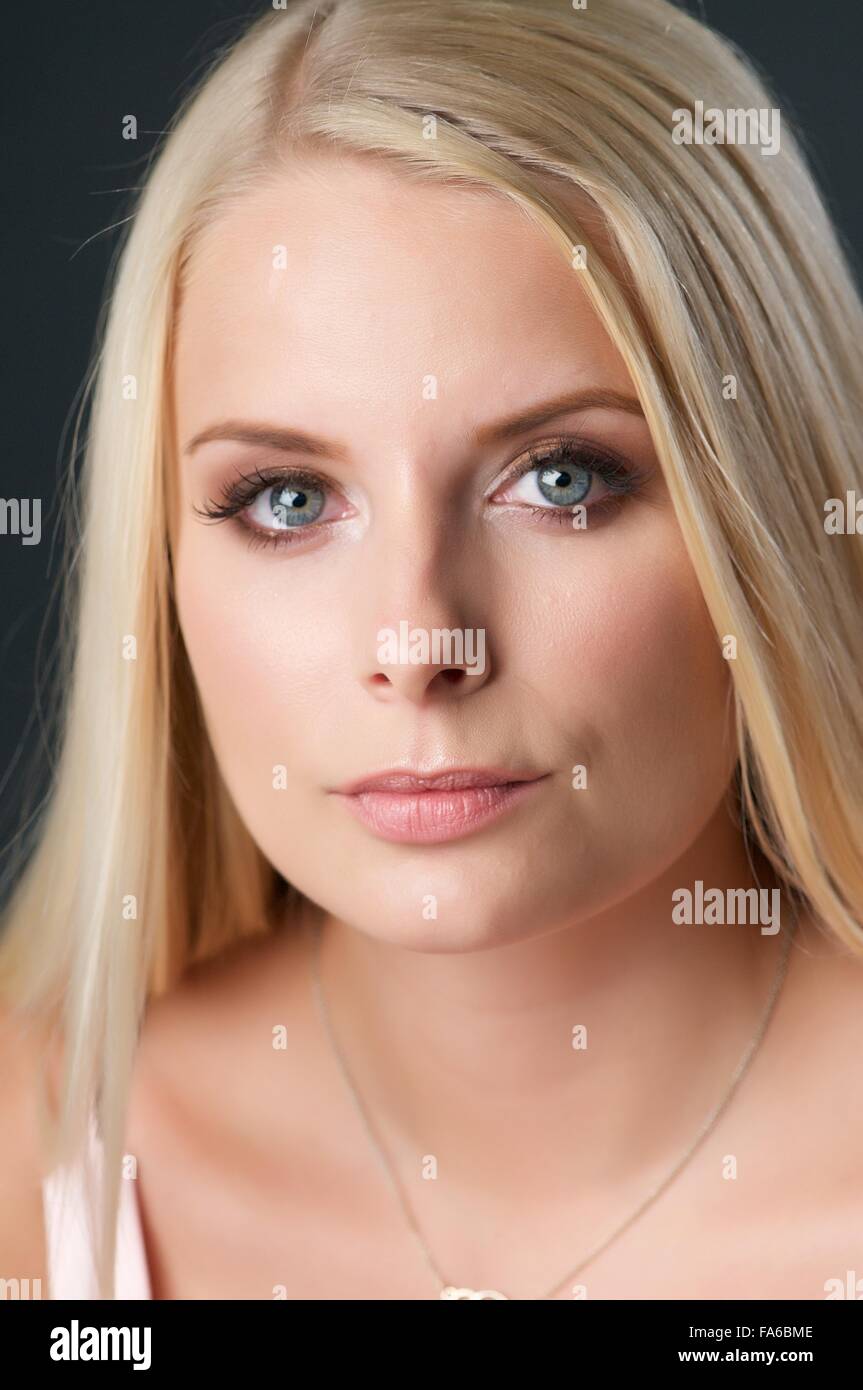 Ein blondes Mädchen in einem niedrig geschnittene leichte rosa Top sitzt im studio Stockfoto