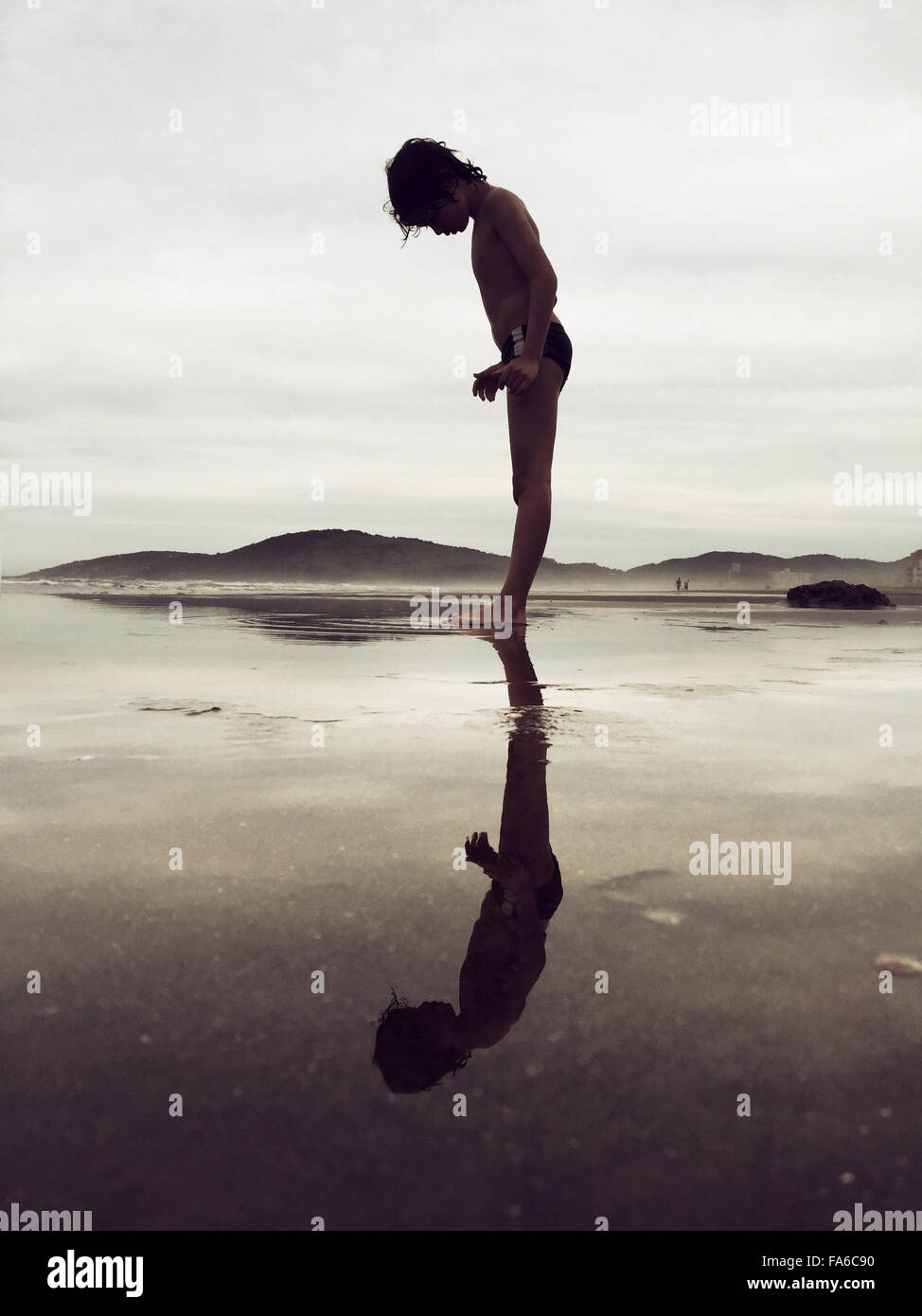 Reflektierte Silhouette der junge Stand am Strand Stockfoto