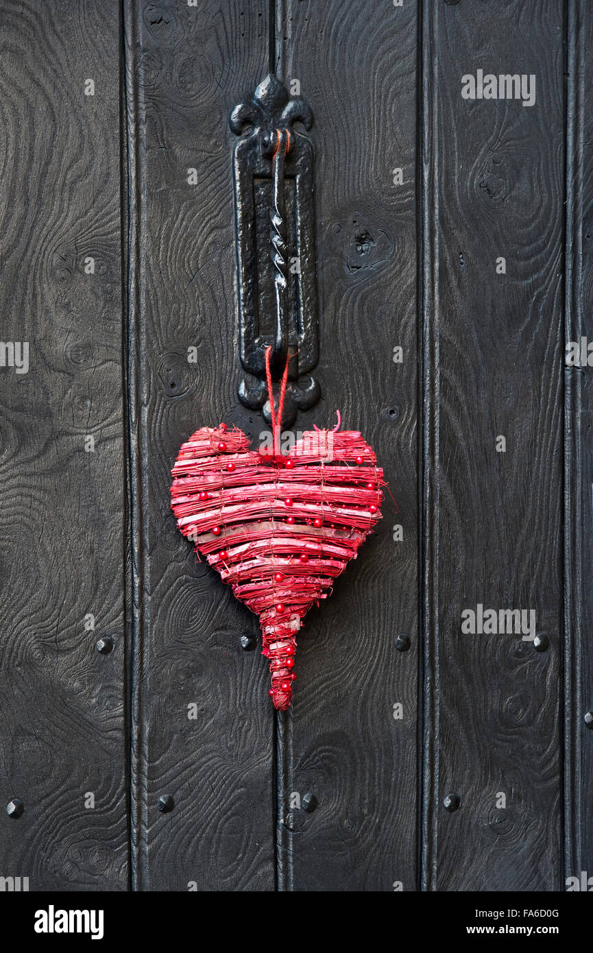Rote Liebe Herzen Weihnachtsdekoration auf eine Holztür. Cotswolds, England Stockfoto