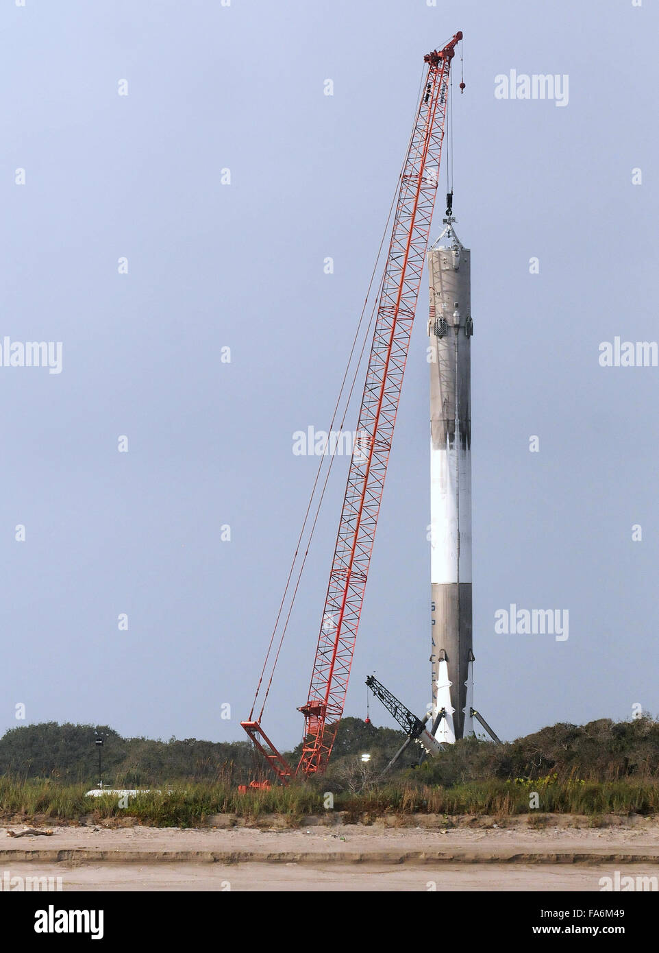 Cape Canaveral, Florida, USA. 22. Dezember 2015. Ein Kran ist gesehen heben die erste Stufe einer SpaceX Falcon 9 Rakete am Morgen, nachdem es 11 ORBCOMM-Kommunikations-Satelliten in die Erdumlaufbahn gestartet, vor der Landung erfolgreich zurück auf Cape Canaveral Air Force Station etwa zehn Minuten später 21. Dezember 2015. Dies ist das erste Mal, das SpaceX eines seiner Raketen an Land gelandet ist. Die historische Leistung stellt einen bedeutenden Schritt in der Technologie der wiederverwendbaren Raketen. Bildnachweis: Paul Hennessy/Alamy Live-Nachrichten Stockfoto