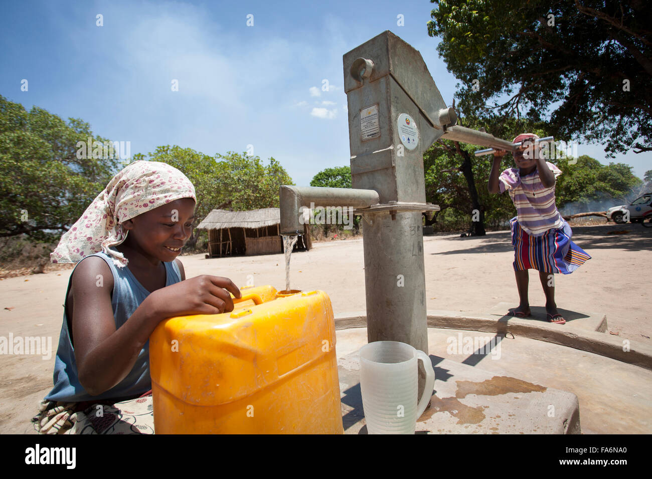 Lurdes Favrito (links) zieht sauberes Wasser aus dem Bohrloch in Mecupes Dorf, Mosambik. Die Millennium Challenge Corporation hat Stockfoto