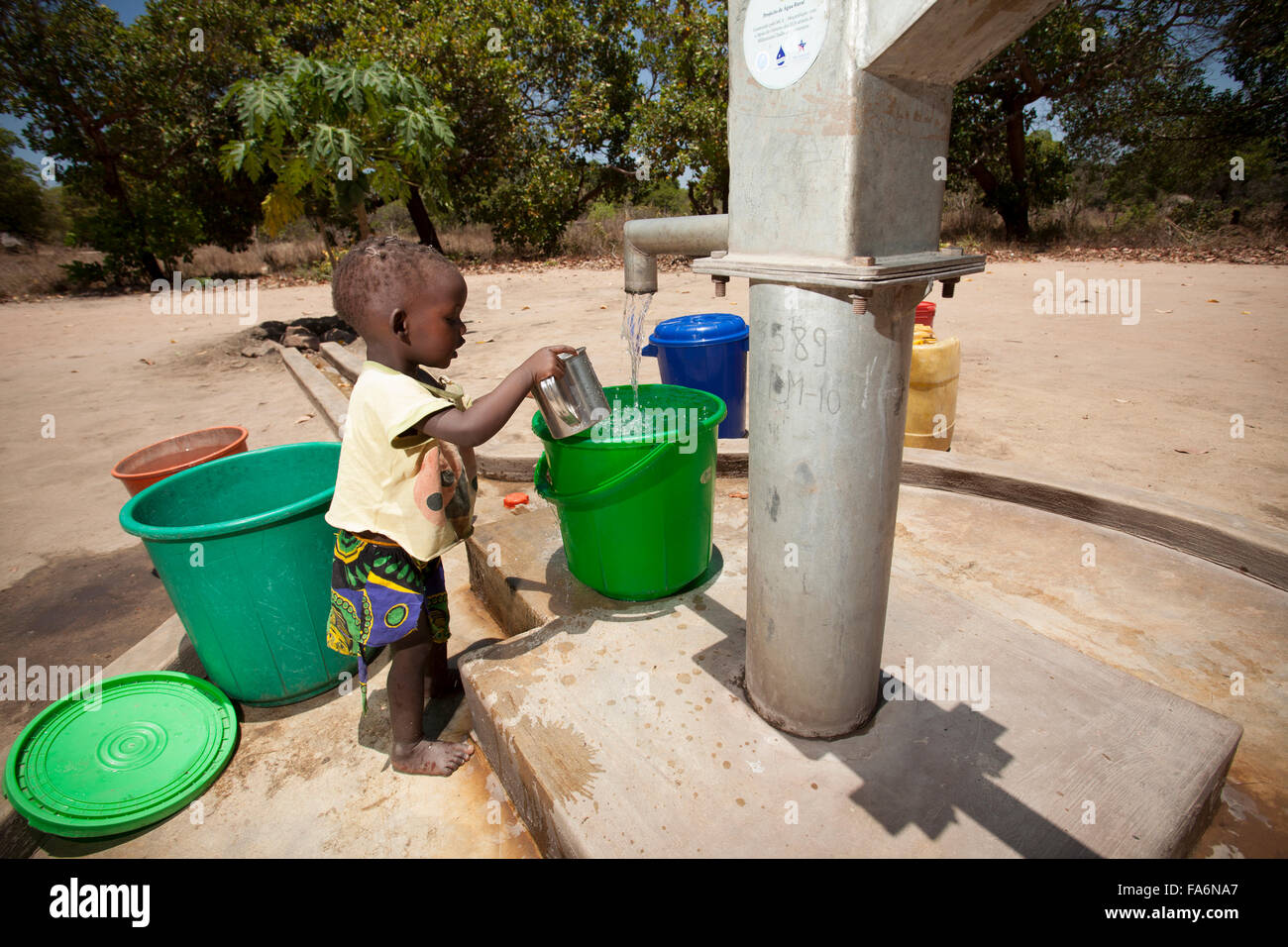 Kinder malen sauberes Wasser aus dem Bohrloch in Mecupes Dorf, Norden Mosambiks. Stockfoto