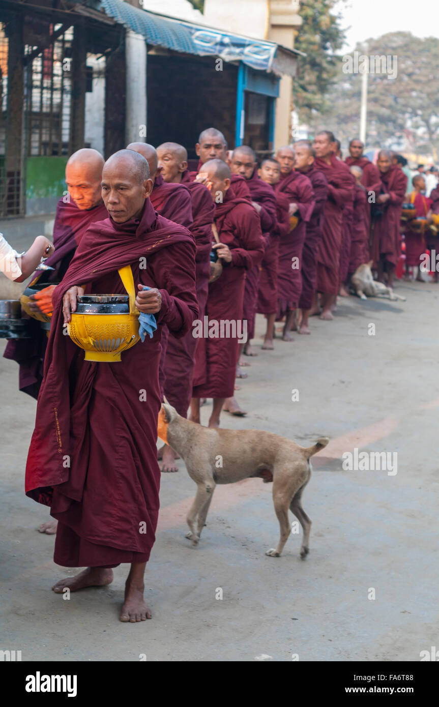 Buddhistischer Mönch in einer langen Schlange in Shwe Kyet noch Dorf in Mandalay, Myanmar, Essen in seine Almosenschale empfangen. Stockfoto