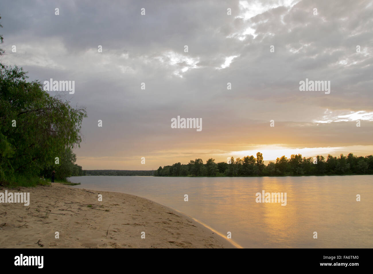 Strand am Fluss bei Sonnenuntergang mit Bäumen Stockfoto