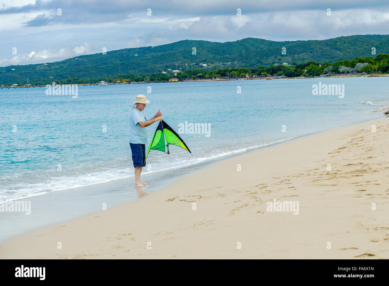 Ein senior Mann hält einen Drachen in der Vorbereitung zu starten es am Strand auf St. Croix, Amerikanische Jungferninseln, Stockfoto