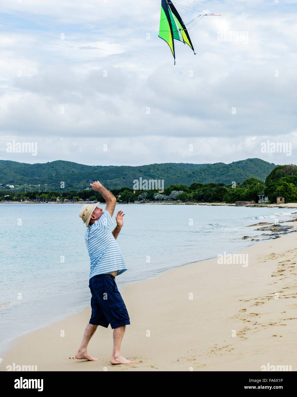 Ein senior kaukasischen Mann wirft einen Drachen in der Luft, einen Freund am Strand von St. Croix, Amerikanische Jungferninseln zu starten. Stockfoto