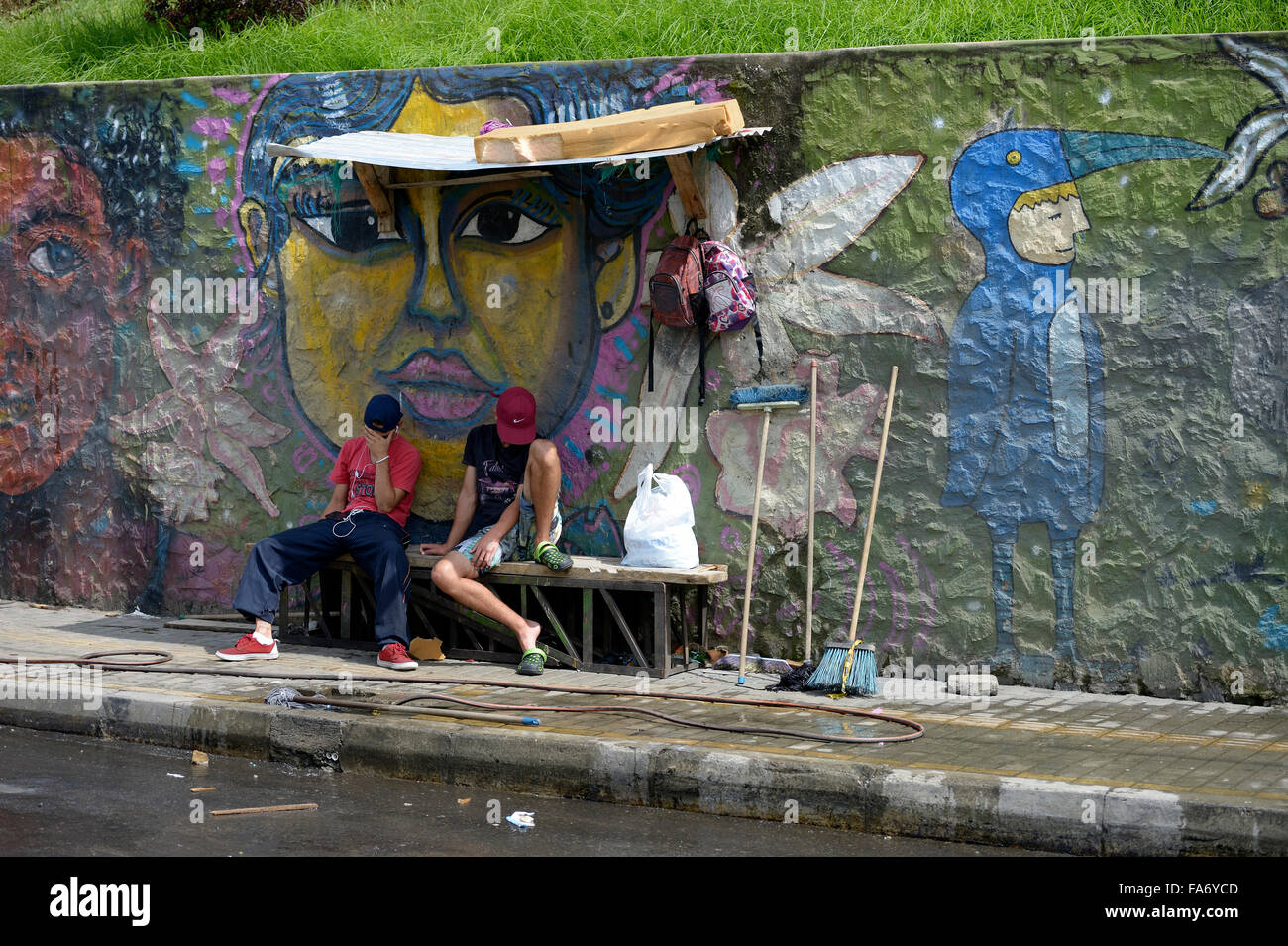 Junge Bandenmitglieder vor Graffitiwand sitzen, Comuna 8 slum, Medellin, Abteilung von Antioquia, Kolumbien Stockfoto