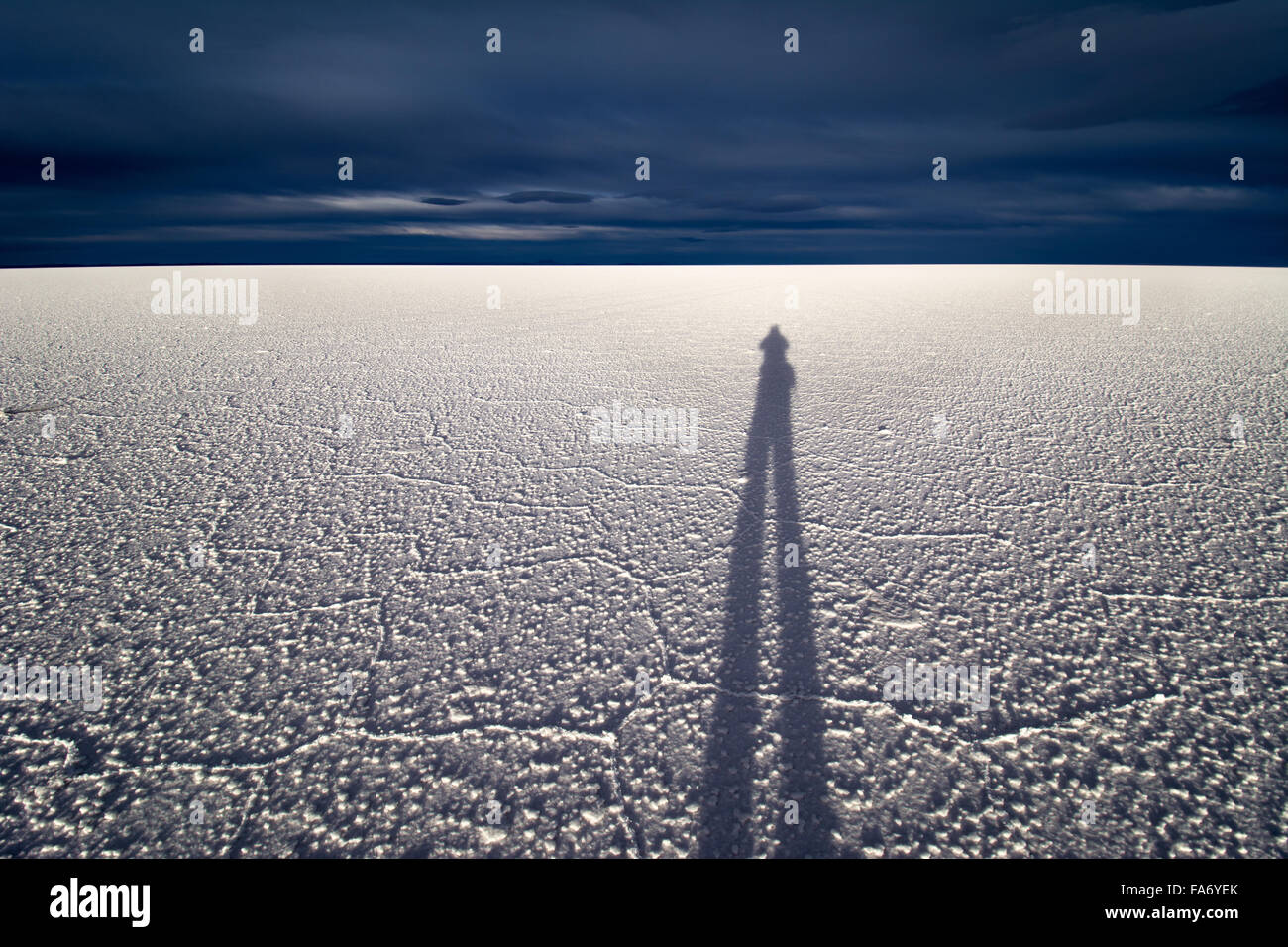 Schatten des Menschen auf Salz flach vor dunklen Wolken, Salar de Uyuni, Altiplano, Bolivien Stockfoto