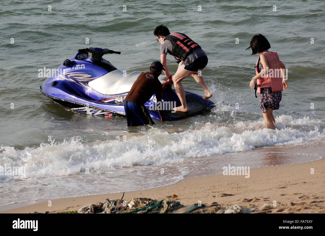 Ein junges Paar Einstellung und Beförderung einen Jetski am Strand von Pattaya in Thailand Stockfoto