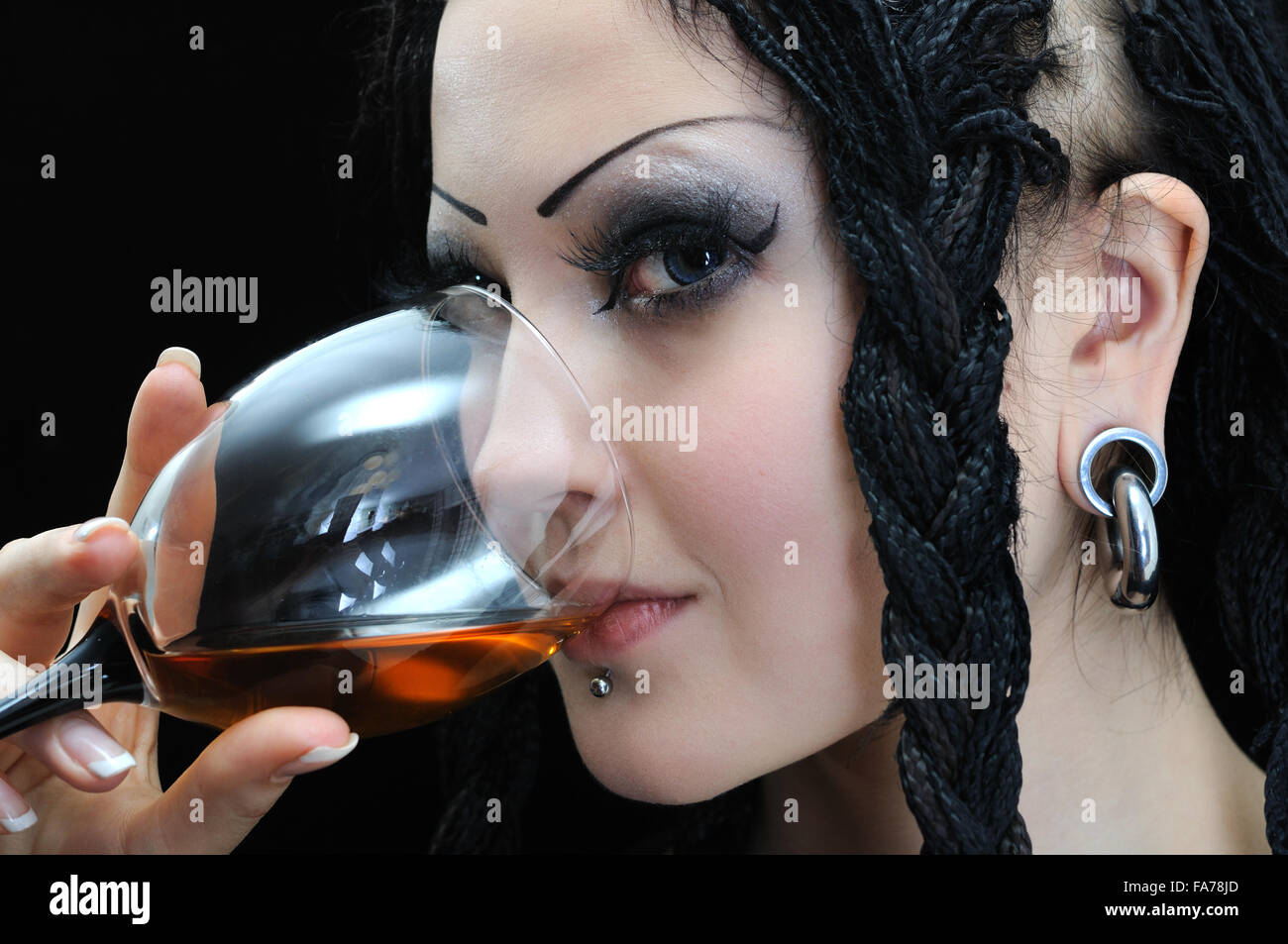 junge stilvolle Frau mit Dreadlocks trinkt Rotwein Stockfoto