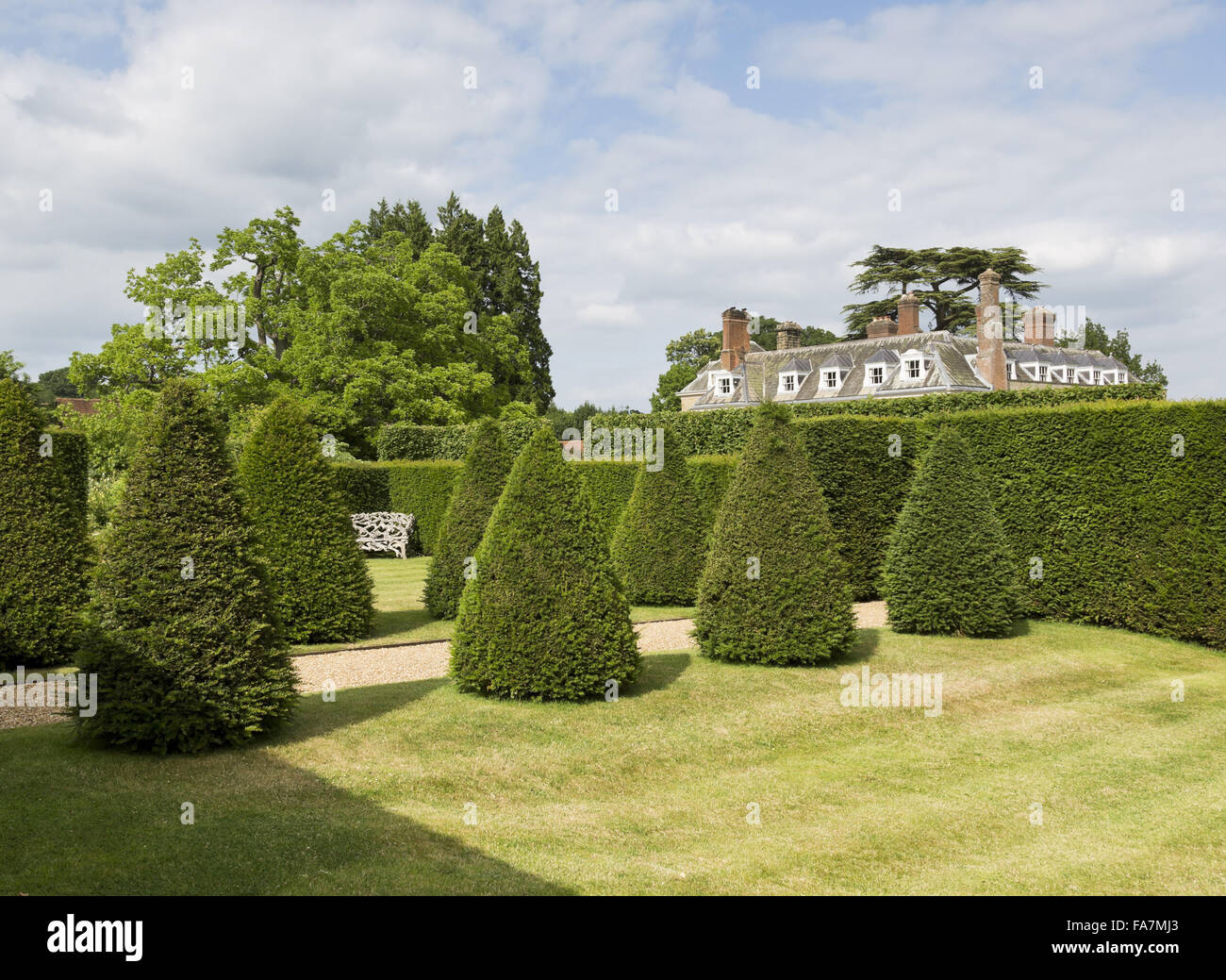 Ein Blick auf das Haus (nicht National Trust) Abend Licht, oben abgeschnitten Eiben, gesehen am Woolbeding Gärten, West Sussex. Woolbeding ist ein modernes Meisterwerk mit Farbe-Themenzimmer Garten und Landschaftsgarten. Stockfoto