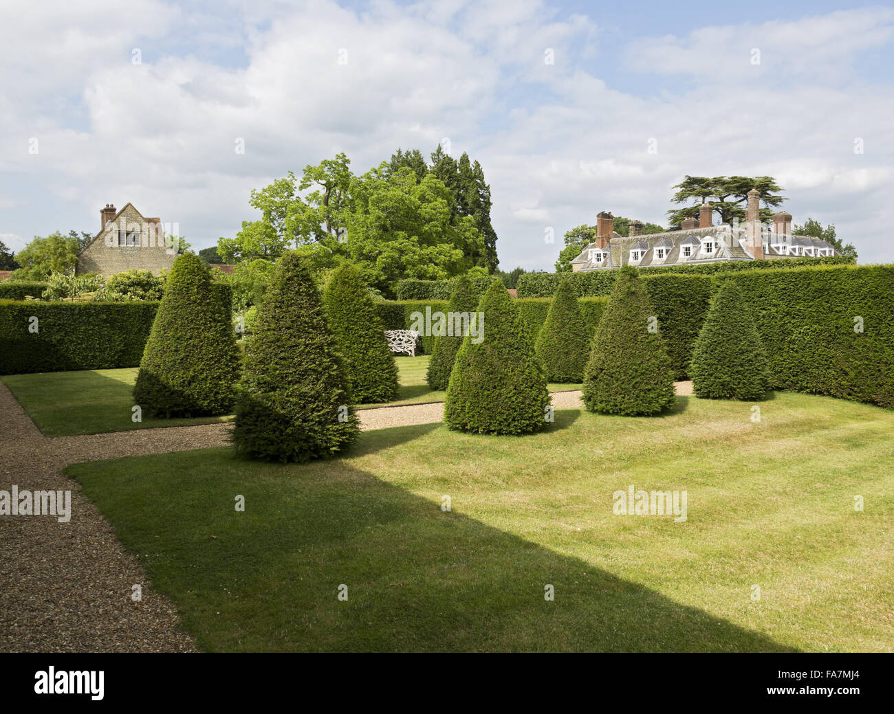 Ein Blick auf das Haus (nicht National Trust) Abend Licht, oben abgeschnitten Eiben, gesehen am Woolbeding Gärten, West Sussex. Woolbeding ist ein modernes Meisterwerk mit Farbe-Themenzimmer Garten und Landschaftsgarten. Stockfoto