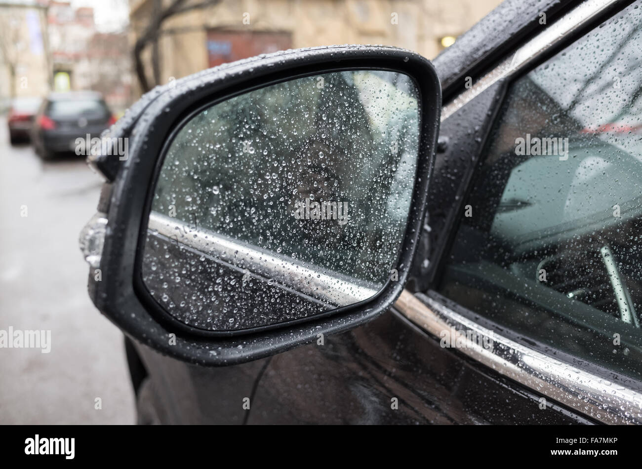 Nassen schwarzen glänzenden Autospiegel mit Regentropfen. Nahaufnahme Foto mit Tiefenschärfe und flachen DOF Stockfoto