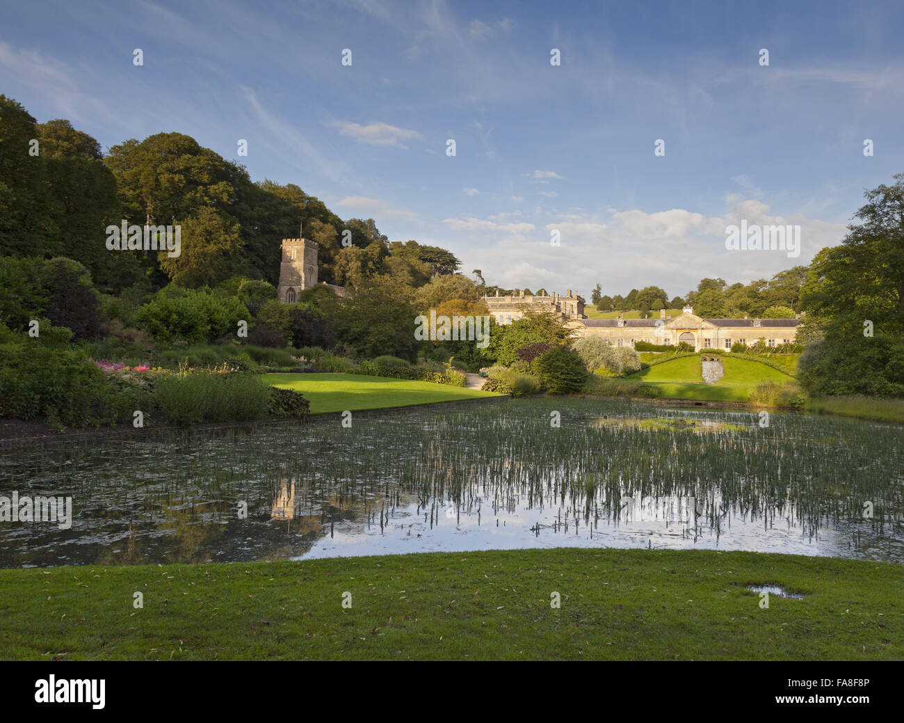 Den Garten und Teich mit Blick auf die Ställe und die Kirche (nicht National Trust) in Dyrham Park, in der Nähe von Bath, South Gloucestershire. Stockfoto