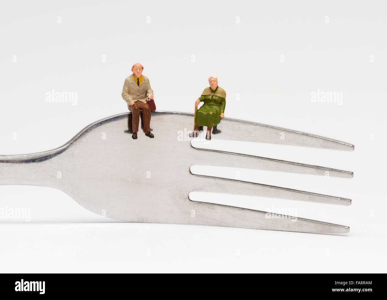 2 Miniatur-Rentner sitzen auf einer Gabel Fütterung Konzept Bild Stockfoto