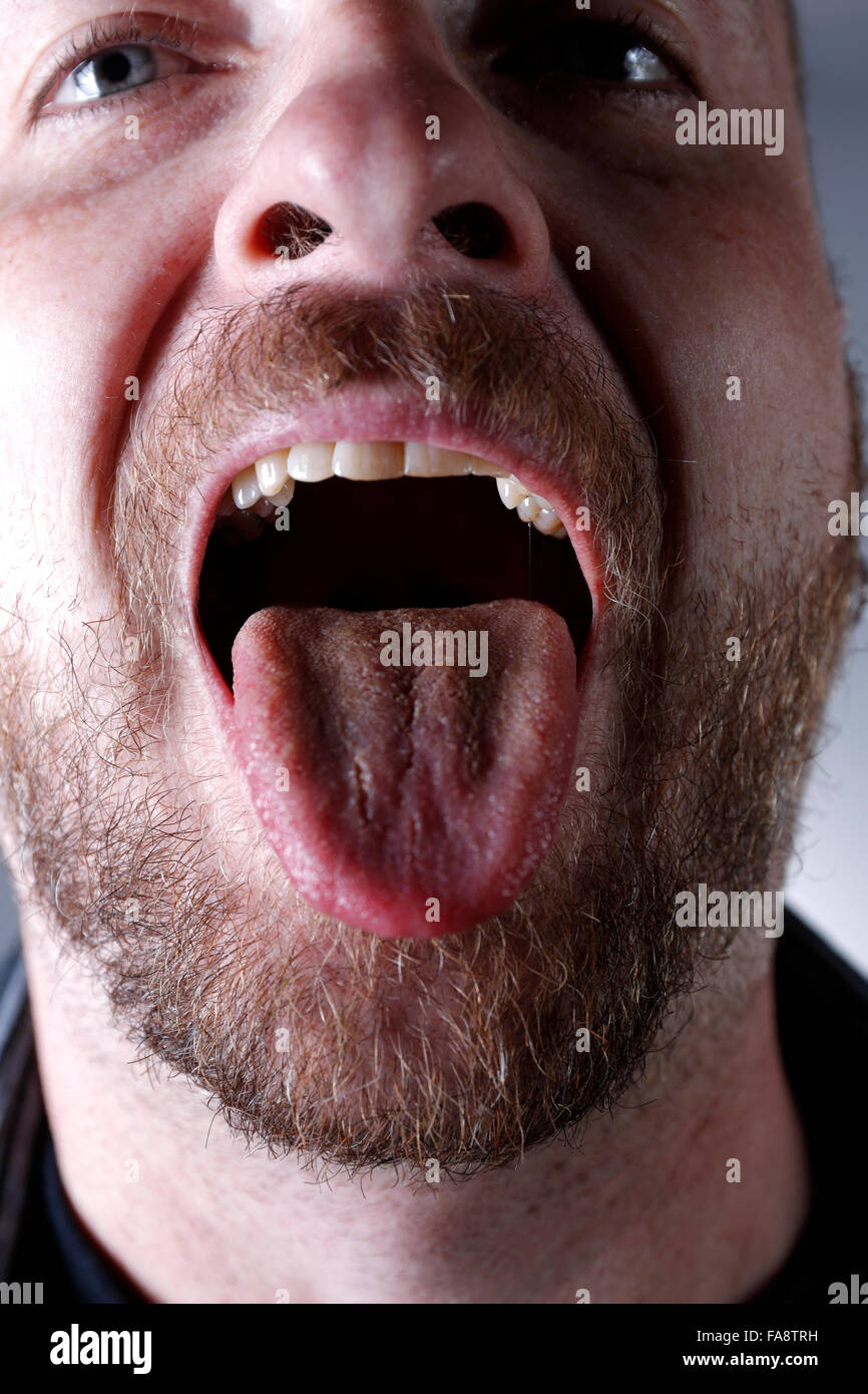 Mann mit Mund geöffnet und zeigt die Zunge. Stockfoto