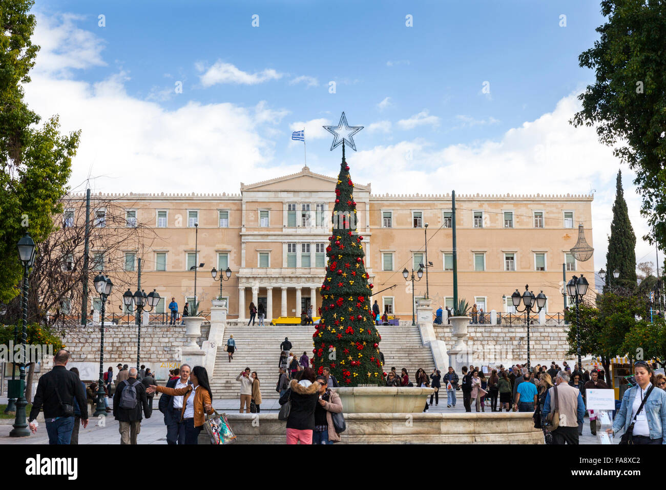 Weihnachtsbaum und Menschen am Syntagma-Platz auf der Ermou, die wichtigste Einkaufsstraße Athens, das griechische Parlament im Hintergrund Stockfoto
