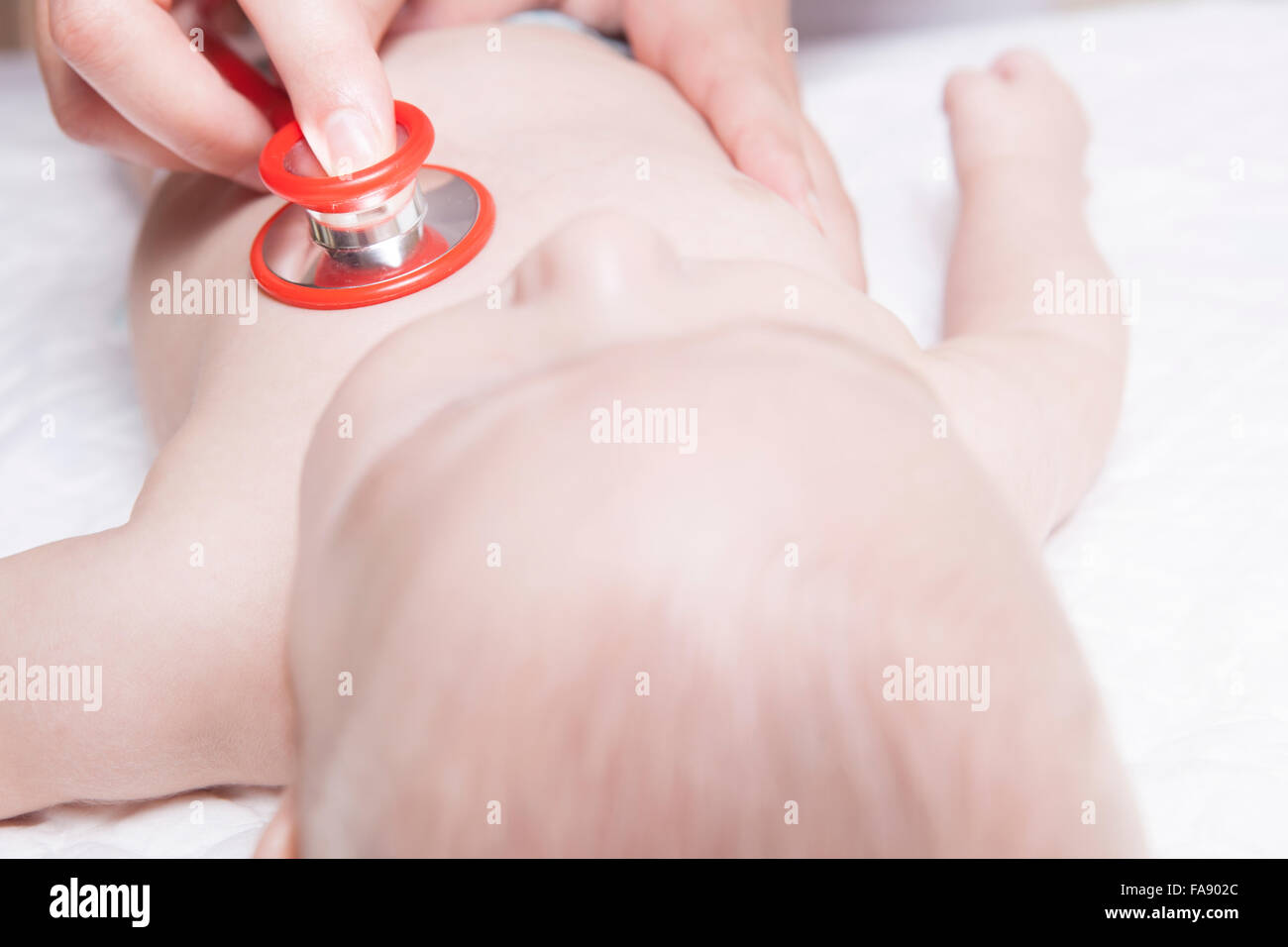 Kinderarzt im weißen Kittel untersucht drei Monate Baby Boy mit einem Stethoskop Stockfoto