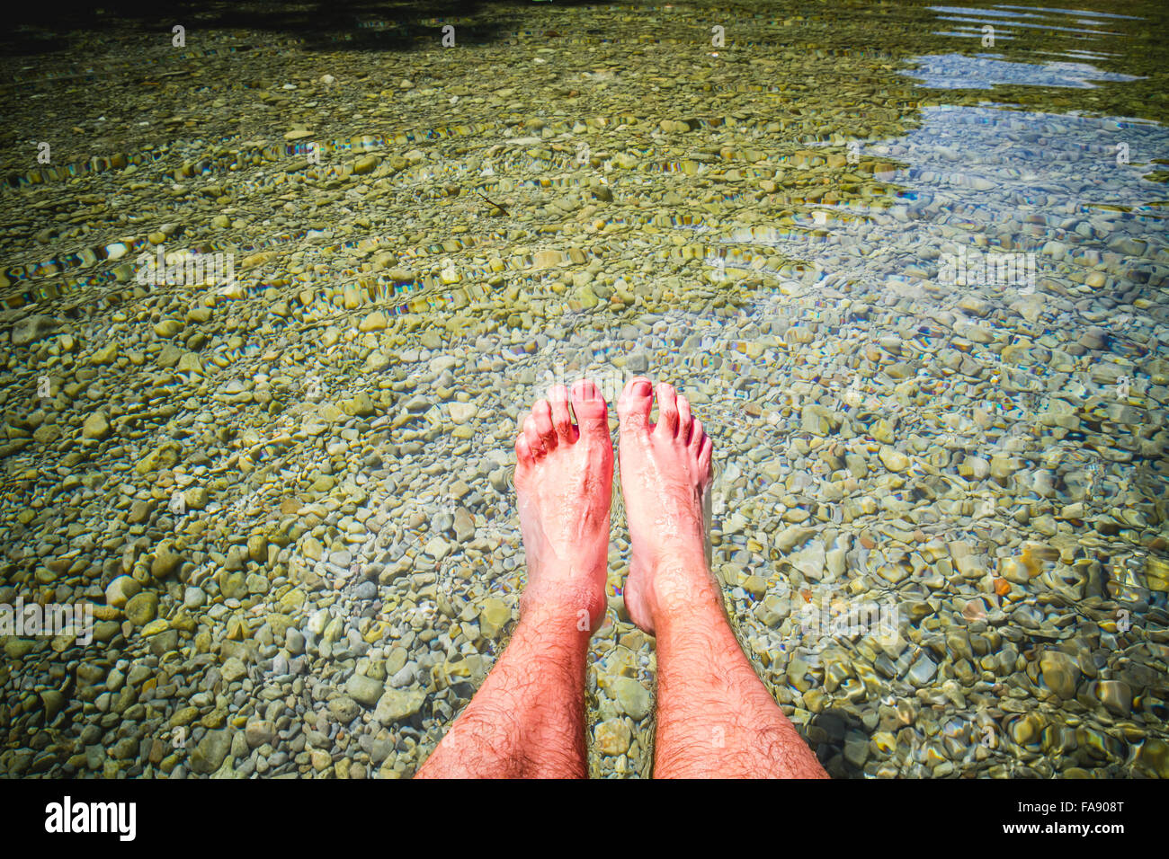 Füße im Sommer durch das Wasser eines Flusses in einem Binnensee Stockfoto