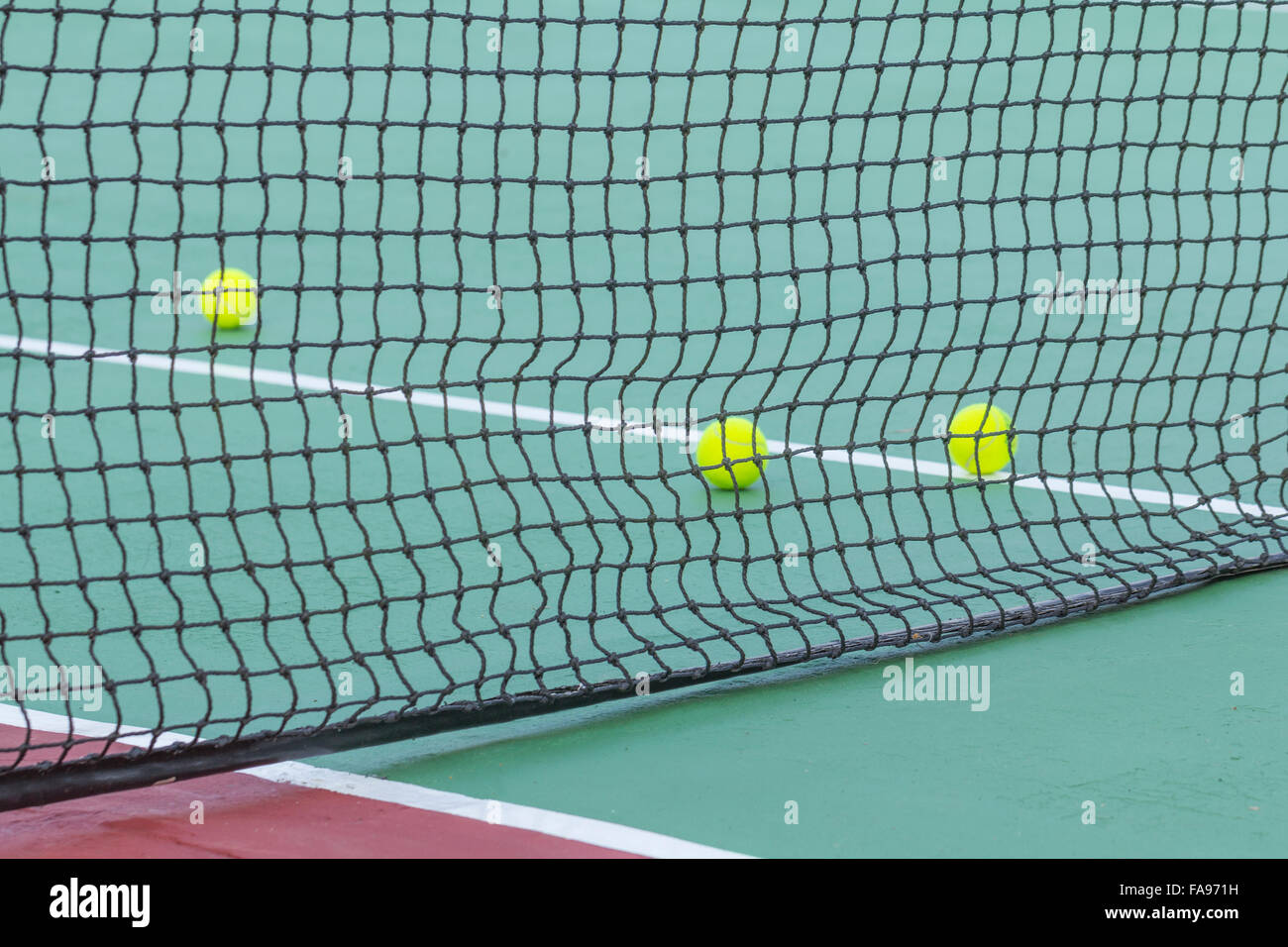 Tennisbälle auf Platz mit Netz Stockfoto