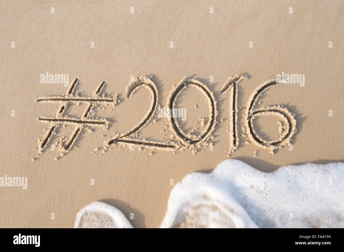 Hashtag-social Media-Nachricht für das Jahr 2016 geschrieben im weichen Sand mit ankommenden Welle am Strand in Rio De Janeiro, Brasilien Stockfoto